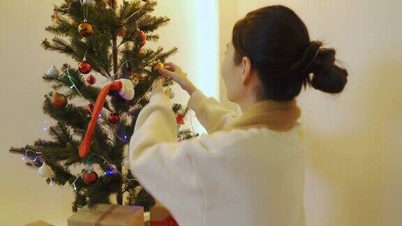 亚洲妇女在客厅装饰圣诞树