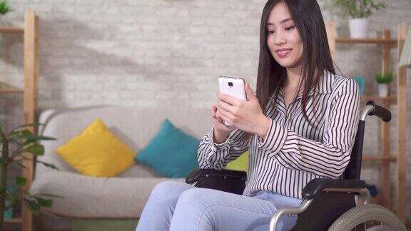 年轻漂亮的亚裔残疾女性坐在轮椅上使用智能手机