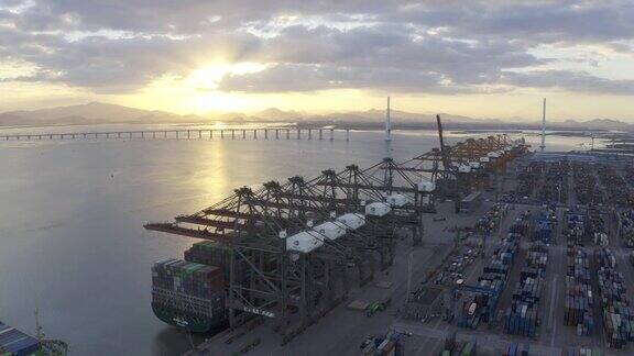 夕阳下几艘大型货轮停在港口装卸集装箱