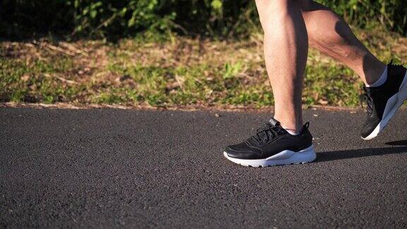 跑步者的脚的特写男人在日落时跑步一个跑步者的腿在公园里跑步的肖像背景是夕阳下的绿树户外运动训练街头运动运动员在户外训练
