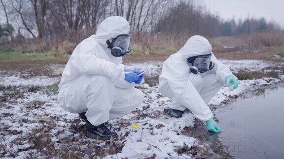 两名穿着防护服的医学研究人员收集污水样本