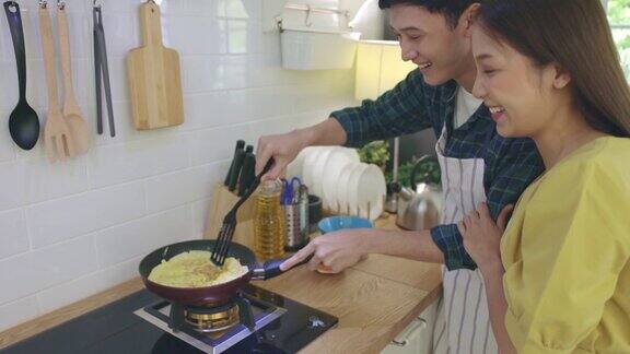 年轻夫妇在家里帮忙做饭营造浪漫的气氛在厨房里情侣们通过帮助对方做早餐来表达爱意