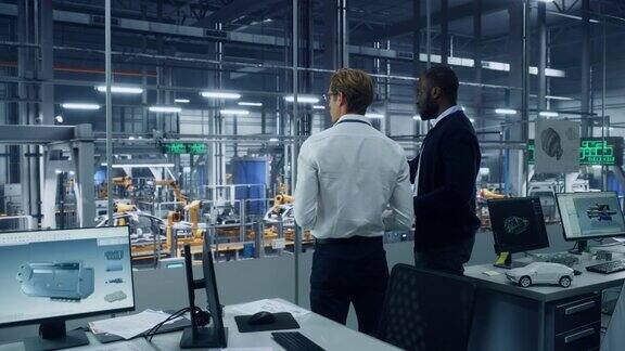 两个不同的汽车工业工程师站在汽车组装厂的办公室谈论汽车生产工业专家讨论平板电脑的工作项目