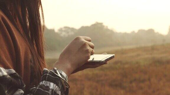 一个女人早上在森林里用智能手机搜索网站的场景