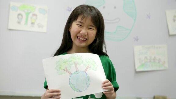 亚洲小女孩的肖像与绿色生态t恤拿着她的图纸拯救世界计划志愿、自然、教育理念