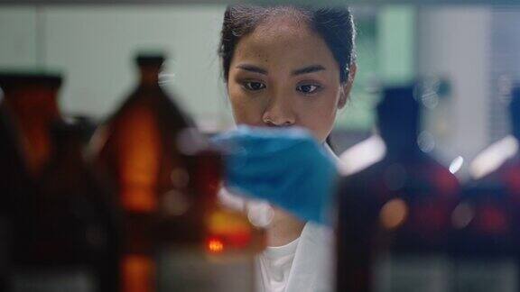 穿着实验室大褂的科学家在实验室工作生物技术实验室的科学家检测烧杯中的液体实验室分析