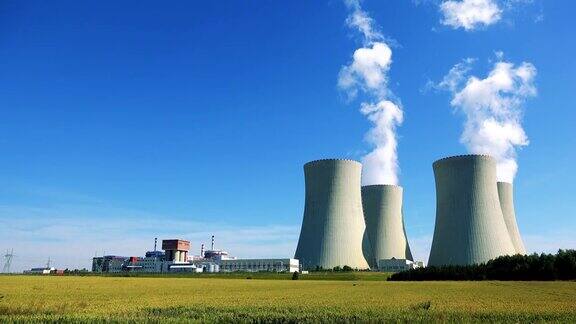 工厂(核电站)-建筑物和烟从烟囱的特写-有工厂和蓝天的田野