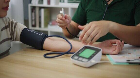男医生在医院用带听诊器的血压计检查病人的血压