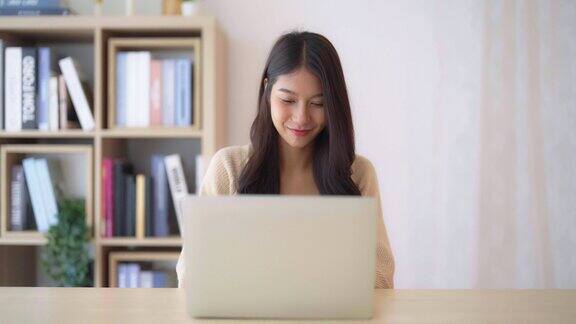 年轻的亚洲女性在家工作女性在家里的桌子上使用笔记本电脑