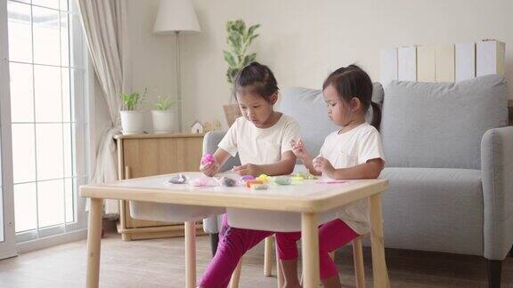 两个快乐的女孩在客厅里一起玩橡皮泥
