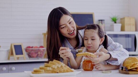 母亲和女儿在家里的厨房里做早餐面包和果酱周末活动快乐家庭生活理念呆在家里母亲节