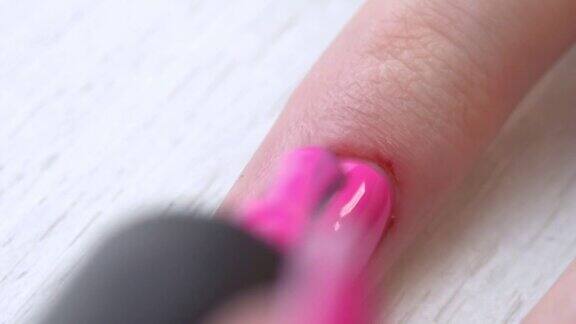 美甲师用粉红色的凝胶指甲油涂指甲独有的美甲服务修剪整齐的粉红色的指甲指甲油的应用程序