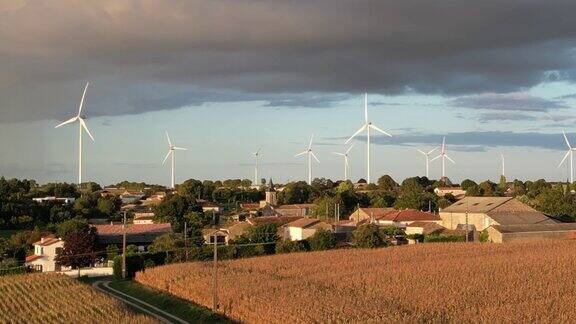 一个法国村庄后面的风力涡轮机上面是灰色的暴风雨云