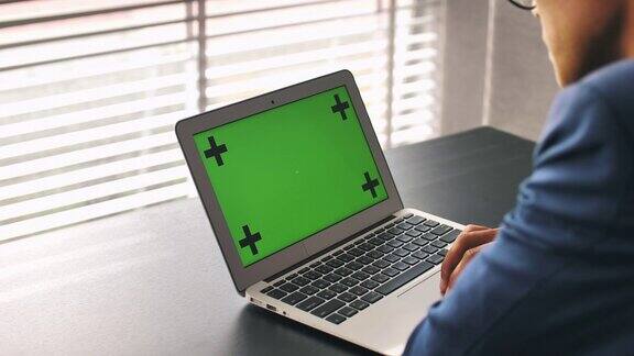 商人的手在笔记本电脑的绿色屏幕上工作