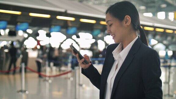 亚洲年轻女商人在机场使用智能手机