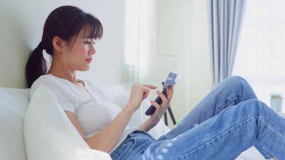 亚洲美女用手机打电话在床上在家里早上快乐随意的漂亮女性躺在卧室享受假日周末在家里用智能手机和科技交流