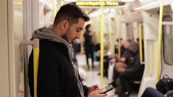 年轻人在地铁里打电话用智能手机玩游戏用手机发短信用手机浏览社交媒体用一只手玩游戏戴着耳机听音乐