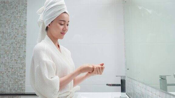 亚洲美女把光滑和皮肤护理为面部柔软迷人的女性轻触面部轻柔地涂抹护肤霜美容、护肤、健康理念