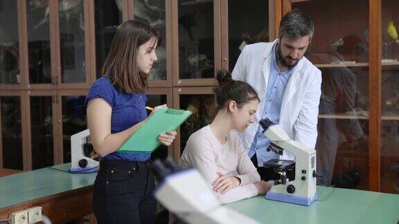 教师在课堂上指导学生使用显微镜