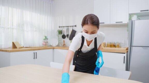 亚洲主动清洁服务女工清洁厨房和家庭年轻漂亮的女管家清洁工戴上口罩心情愉快地擦拭着脏乱的桌子为家政做家务或杂务