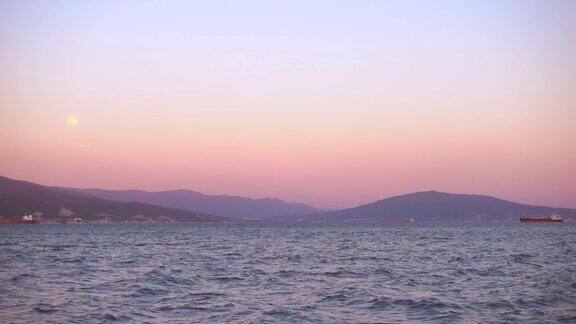 美丽的夕阳和月亮照耀着港口城市远处有船只