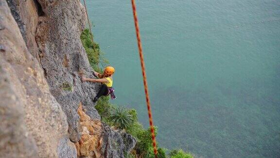成熟的亚洲女人在热带岛屿的岩石山上攀岩暑假