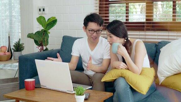 两个年轻的亚洲夫妇家庭放松在沙发上工作的笔记本电脑商业金融亚洲生活方式在家里