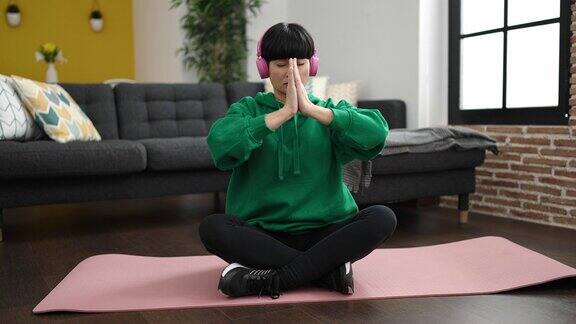 年轻的中国女子在家里听音乐做瑜伽练习