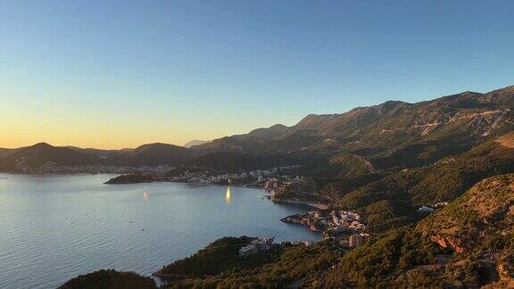 海湾岸边的山脉在落日的余晖中映衬着蓝黄色的天空