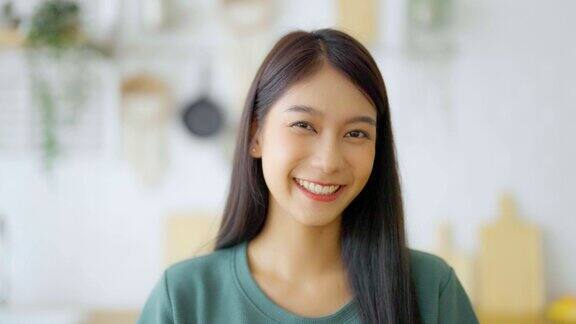 肖像微笑的亚洲年轻女子看相机面部表情快乐