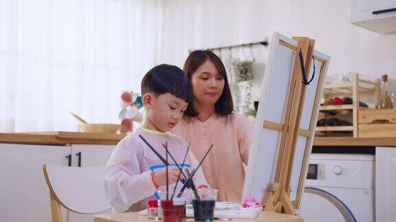 可爱的亚洲小儿子在纸上画画父母在家里快乐的家庭活动小男孩们在家里的客厅里和妈妈一起学习如何画艺术品享受创造力