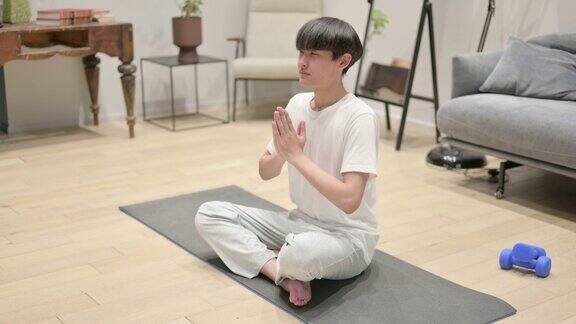 年轻的亚洲男子在家冥想瑜伽垫
