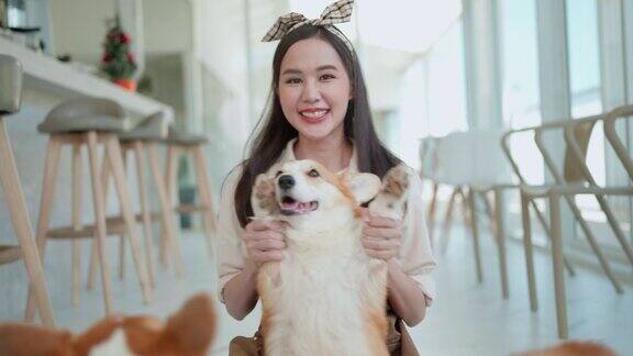 亚洲女狗柯基咖啡馆员工穿着制服照顾小狗狗抱着微笑和欢快的狗狗咖啡馆内部背景