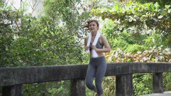 年轻美丽的亚洲女性跑步者穿着运动服与毛巾在公园户外跑步或慢跑适合慢跑女性锻炼早上进行运动训练锻炼