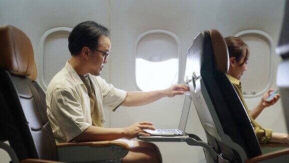 4K亚洲商人在飞机上旅行时用笔记本电脑工作