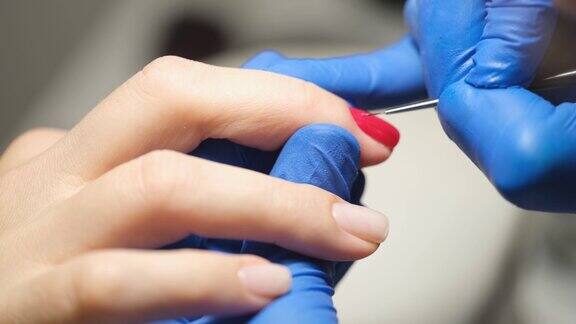 美容院的美甲师在女性手指上涂红色指甲油