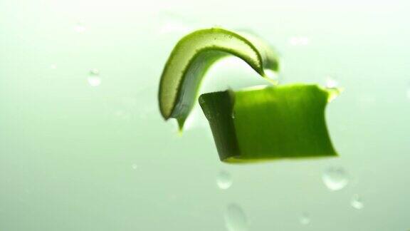 俯视图芦荟片吸液管与芦荟汁滴在多汁的切片芦荟叶在绿色背景天然化妆品