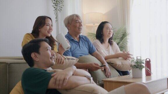 亚洲家庭在家里度过安静的夜晚妈妈、女儿和爷爷坐在沙发上看电视