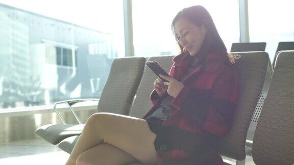 一位女士在机场用手机等待航班