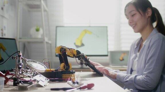 女工程师使用机械臂工作她使用数字平板控制机械臂