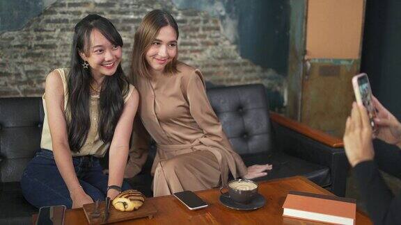 一群亚洲女性朋友聚在咖啡厅用智能手机拍照