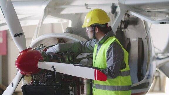 飞机工程师在飞机库里检查飞机引擎然后把它放回飞行
