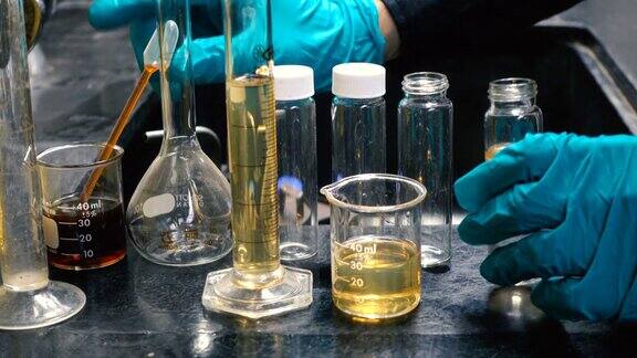 戴绿色手套的医学或化学实验室科学家使用移液管向试管中填充液体进行实验医药实验室生物技术研究人员