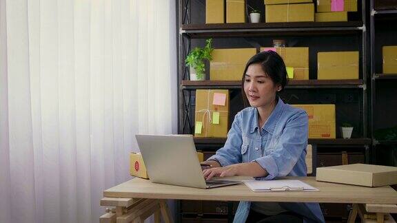 年轻的亚洲女性自由职业者使用她的笔记本电脑和在家里工作小企业女性业主或启动小企业企业家工作在线营销包装盒配送