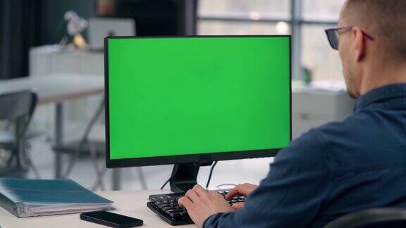 年轻人在办公室用绿色的模拟屏幕工作