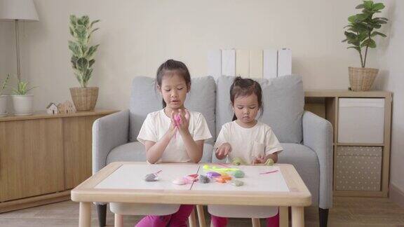 两个快乐的女孩在客厅里玩小粘土玩得很开心