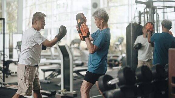 亚洲华人高级男子练习拳击对打在健身房例行的周末活动