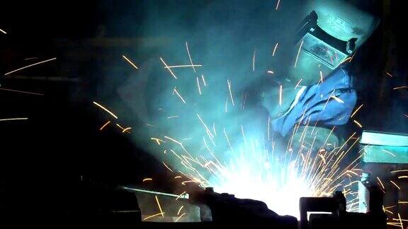 产业工人正在生产线上用防护面罩焊接金属