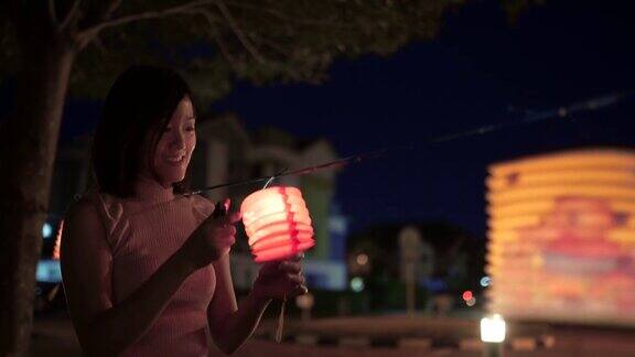 亚洲华人妇女在纸灯笼里点燃蜡烛庆祝节