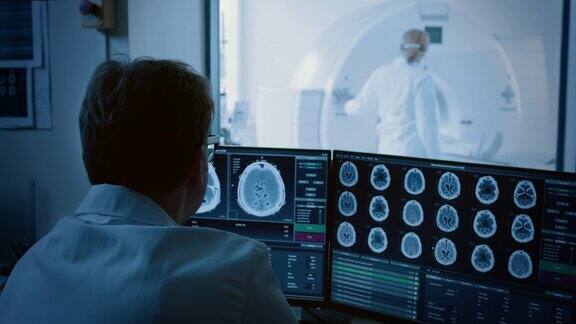 在医学实验室病人在放射科医生的监督下接受MRI或CT扫描过程在控制室医生观察过程并监测大脑扫描结果